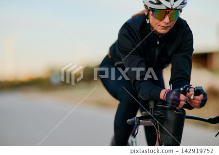 Female Cyclist Training on Road Bike With Aero Bars Wearing Helmet and Reflective Sunglasses Female Cyclist Training on Road Bike With Aero Bars Wearing Helmet and Reflective Sunglasses 142919752