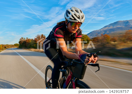 Female Cyclist Training on Road Bike in Aerodynamic Position Through Countryside at Speed Female Cyclist Training on Road Bike in Aerodynamic Position Through Countryside at Speed 142919757
