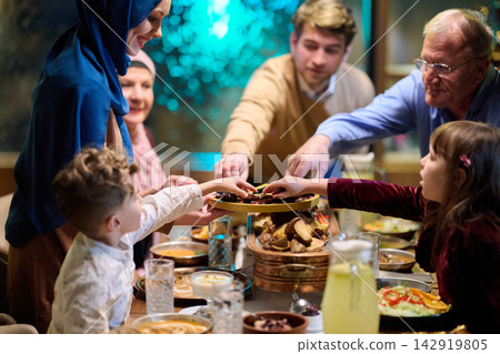 Muslim Family Sharing Dates and Food at Festive Evening Dinner Around a Warm Table Muslim Family Sharing Dates and Food at Festive Evening Dinner Around a Warm Table 142919805