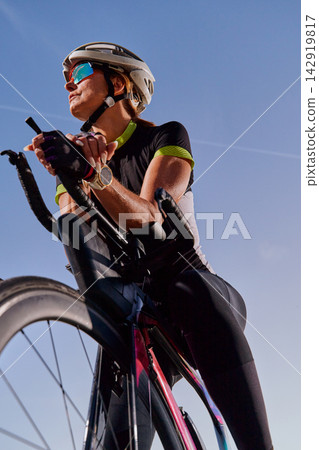Female Cyclist on Road Bike in Helmet and Sunglasses Training Outdoors Under Clear Blue Sky Female Cyclist on Road Bike in Helmet and Sunglasses Training Outdoors Under Clear Blue Sky 142919817