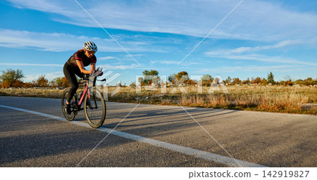 Female Cyclist Training on Open Road at Sunrise for Endurance Road Biking Exercise Female Cyclist Training on Open Road at Sunrise for Endurance Road Biking Exercise 142919827