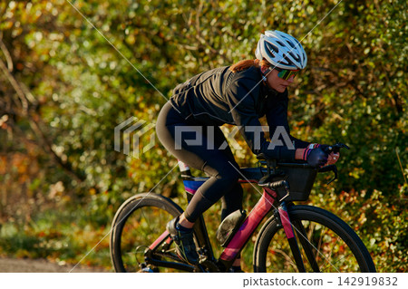 Female Cyclist Training on Road Bike in Autumn Countryside Wearing Helmet and Sunglasses Female Cyclist Training on Road Bike in Autumn Countryside Wearing Helmet and Sunglasses 142919832