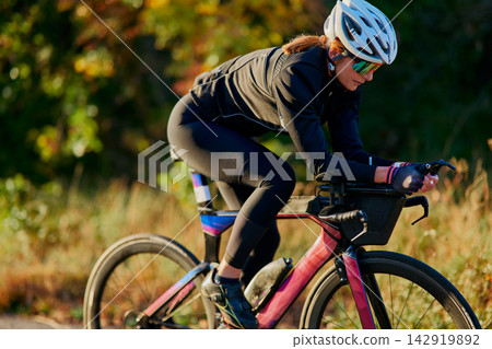 Female Cyclist Training On Aero Road Bike Outdoors During Autumn Morning Ride For Fitness Female Cyclist Training On Aero Road Bike Outdoors During Autumn Morning Ride For Fitness 142919892