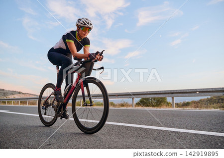 Female Road Cyclist Training On Open Highway At Sunrise With Aerodynamic Time Trial Bike Female Road Cyclist Training On Open Highway At Sunrise With Aerodynamic Time Trial Bike 142919895
