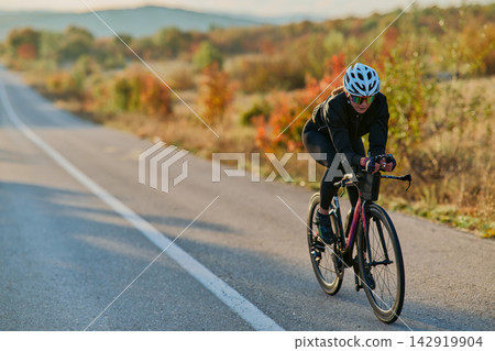 Female Cyclist Training On Road Bike Through Autumn Countryside At Sunrise Fitness Ride Female Cyclist Training On Road Bike Through Autumn Countryside At Sunrise Fitness Ride 142919904