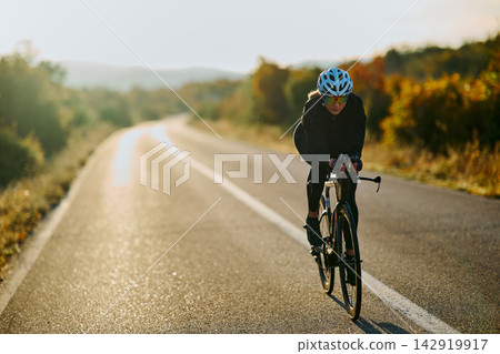 Female Cyclist Training on Quiet Country Road at Sunrise in Autumn Fitness Cycling Workout Female Cyclist Training on Quiet Country Road at Sunrise in Autumn Fitness Cycling Workout 142919917