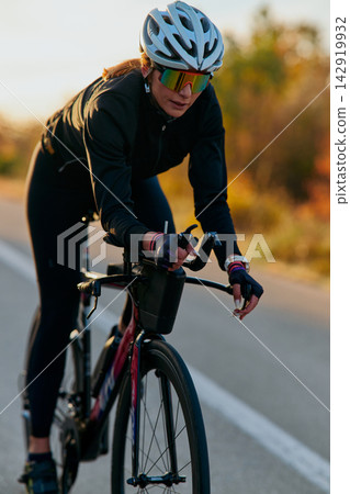 Female Cyclist Riding Road Bike At Sunset Training Outdoors With Helmet And Sunglasses Female Cyclist Riding Road Bike At Sunset Training Outdoors With Helmet And Sunglasses 142919932