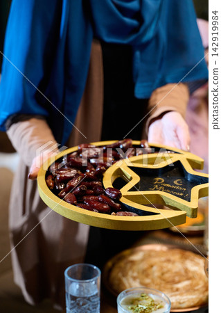 Woman Holding Crescent and Star Tray of Dates for Ramadan Iftar Celebration and Traditional Hospitality Woman Holding Crescent and Star Tray of Dates for Ramadan Iftar Celebration and Traditional Hospitality 142919984