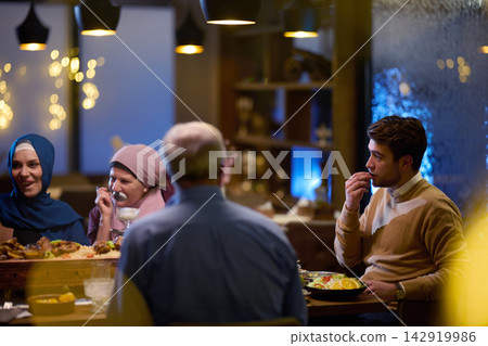 Muslim Family and Friends Sharing Warm Evening Iftar Dinner in Restaurant Celebration Muslim Family and Friends Sharing Warm Evening Iftar Dinner in Restaurant Celebration 142919986