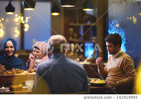 Multigenerational Family Dinner With Women Wearing Hijab Sharing Food and Conversation at Restaurant Multigenerational Family Dinner With Women Wearing Hijab Sharing Food and Conversation at Restaurant 142919995