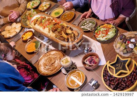 Family Gathering Around A Festive Shared Dinner Table With Middle Eastern Cuisine And Desserts Family Gathering Around A Festive Shared Dinner Table With Middle Eastern Cuisine And Desserts 142919997