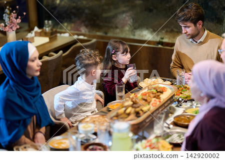 Multigenerational Family Sharing a Festive Dinner Around a Large Table in Warm Interior 142920002