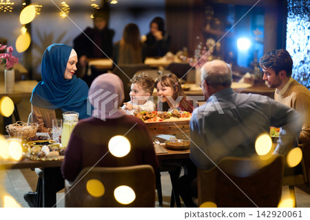Multi Generational Muslim Family Enjoying Warm Dinner Together at Restaurant With Large Shared Platter Multi Generational Muslim Family Enjoying Warm Dinner Together at Restaurant With Large Shared Platter 142920061