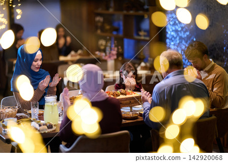 Muslim Family Praying Together Before Iftar Dinner in Warm Festive Home Setting 142920068