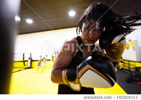 Determined Female Boxer Training With Gloves in Bright Boxing Gym During Intense Workout Session Determined Female Boxer Training With Gloves in Bright Boxing Gym During Intense Workout Session 142920151