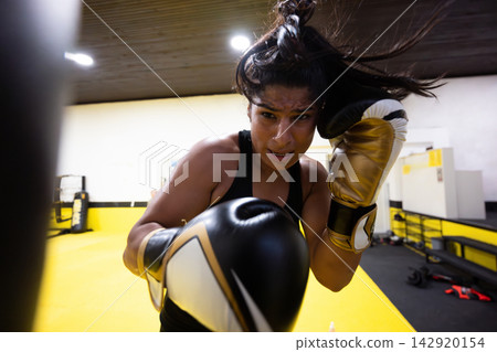 Female Boxer Training Intense Boxing Workout With Gold Gloves In Gym Showing Focus And Determination Female Boxer Training Intense Boxing Workout With Gold Gloves In Gym Showing Focus And Determination 142920154