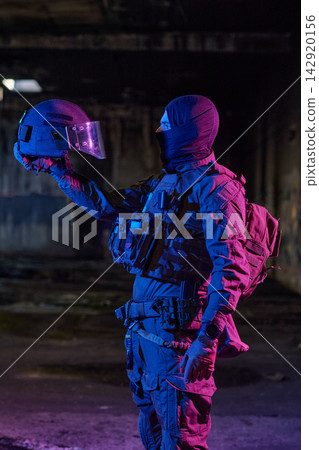 Tactical Soldier In Balaclava Holding Riot Helmet In Dark Urban Military Scene With Neon Lighting Tactical Soldier In Balaclava Holding Riot Helmet In Dark Urban Military Scene With Neon Lighting 142920156