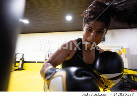 Determined Female Boxer Training Intense Workout In Bright Boxing Gym With Gloves And Focused Expression Determined Female Boxer Training Intense Workout In Bright Boxing Gym With Gloves And Focused Expression 142920157