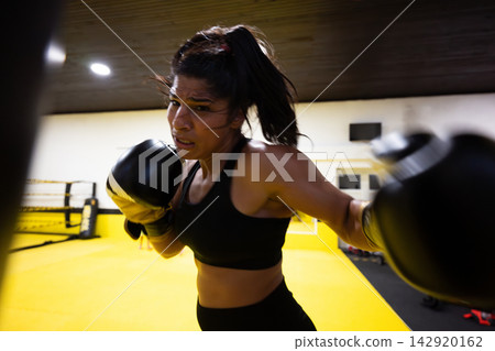 Female Boxer Training in Gym Throwing Punches During Intense Boxing Workout Sparring Session Female Boxer Training in Gym Throwing Punches During Intense Boxing Workout Sparring Session 142920162