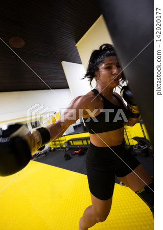 Female Boxer Training Punching Bag Intense Fitness Workout In Gym With Gloves And Focus 142920177