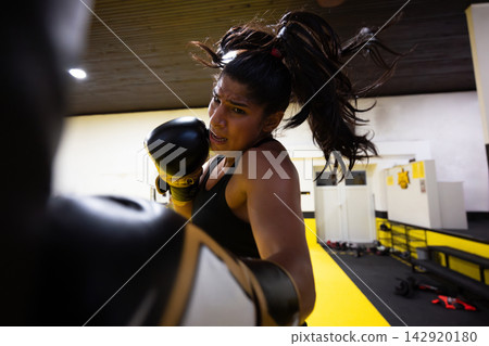 Female Boxer Training Intense Punching Motion in Gym Showing Strength, Focus and Determination Female Boxer Training Intense Punching Motion in Gym Showing Strength, Focus and Determination 142920180