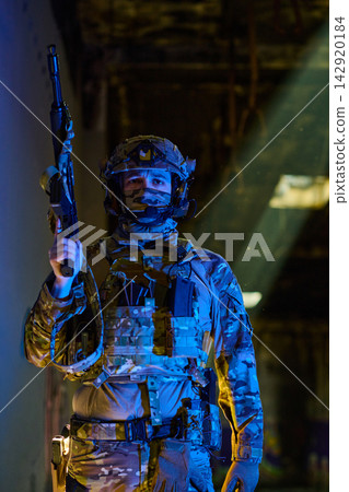 Armed Soldier in Tactical Gear Holding Rifle Under Dramatic Light in Urban Military Scene Armed Soldier in Tactical Gear Holding Rifle Under Dramatic Light in Urban Military Scene 142920184