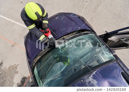 Firefighter Performing Vehicle Rescue Extraction With Hydraulic Cutter On Crashed Car Windshield Firefighter Performing Vehicle Rescue Extraction With Hydraulic Cutter On Crashed Car Windshield 142920189