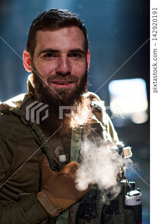 Bearded Soldier in Tactical Gear Smiling While Cold Breath Is Visible in Dim Light Bearded Soldier in Tactical Gear Smiling While Cold Breath Is Visible in Dim Light 142920191