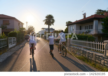 Family Cycling Together At Sunset On A Quiet Residential Street Near Umag Family Cycling Together At Sunset On A Quiet Residential Street Near Umag 142920195