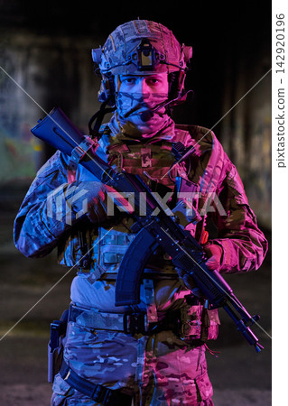 Armed Soldier In Tactical Gear With Assault Rifle Wearing Helmet And Camouflage In Urban Night Scene Armed Soldier In Tactical Gear With Assault Rifle Wearing Helmet And Camouflage In Urban Night Scene 142920196