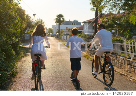 Family Cycling Together on a Sunny Suburban Street During Summer Vacation Morning Ride Family Cycling Together on a Sunny Suburban Street During Summer Vacation Morning Ride 142920197
