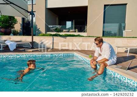 Father and Son Enjoying Morning at Private Pool Beside Modern Luxury Home Patio 142920232