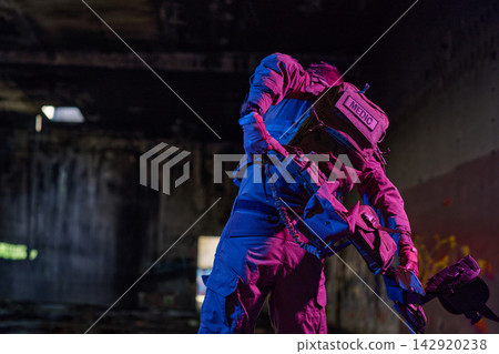 Tactical Medic In Gear Carrying Equipment Inside Dark Abandoned Urban Building With Neon Lighting Tactical Medic In Gear Carrying Equipment Inside Dark Abandoned Urban Building With Neon Lighting 142920238
