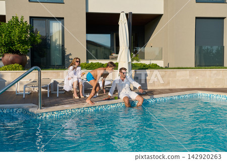 Family Relaxing By A Private Pool At A Luxury Villa During A Sunny Summer Vacation Family Relaxing By A Private Pool At A Luxury Villa During A Sunny Summer Vacation 142920263