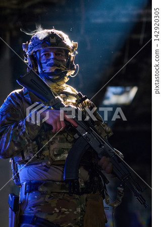Armed Tactical Soldier in Camouflage Gear Holding Rifle in Low Light Urban Environment Armed Tactical Soldier in Camouflage Gear Holding Rifle in Low Light Urban Environment 142920305