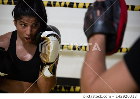 Female Boxer Training With Coach Focused On Defense In Boxing Gym During Intense Mitt Work Female Boxer Training With Coach Focused On Defense In Boxing Gym During Intense Mitt Work 142920318