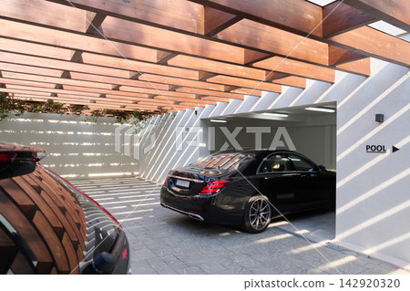 Luxury Black Car Parked Under Wooden Pergola Near Pool Entrance in Modern Garage Luxury Black Car Parked Under Wooden Pergola Near Pool Entrance in Modern Garage 142920320
