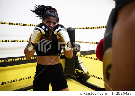 Female Boxer Training in Ring Wearing Gloves During Intense Sparring Session for Fitness Female Boxer Training in Ring Wearing Gloves During Intense Sparring Session for Fitness 142920425