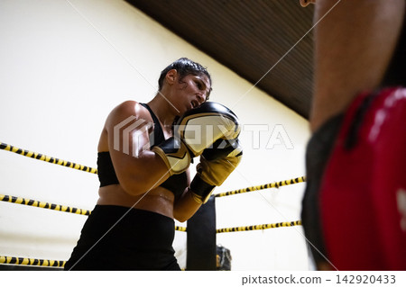 Female Boxer Training in Gym Ring During Intense Sparring Session With Coach Partner Female Boxer Training in Gym Ring During Intense Sparring Session With Coach Partner 142920433