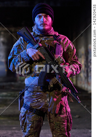 Armed Soldier in Camouflage Tactical Gear Holding Rifle in Urban Night Setting Armed Soldier in Camouflage Tactical Gear Holding Rifle in Urban Night Setting 142920438