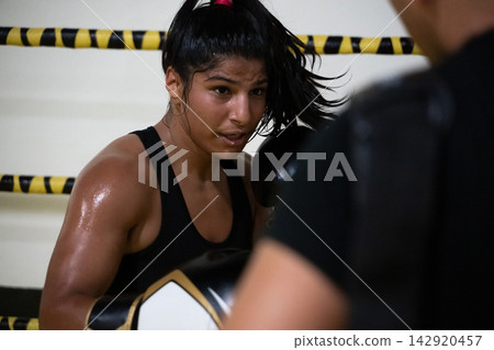 Determined Female Boxer Training in Ring During Intense Sparring Session With Coach Determined Female Boxer Training in Ring During Intense Sparring Session With Coach 142920457