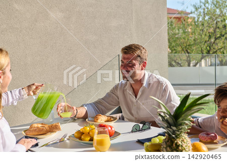 Family Breakfast On Sunny Terrace With Father, Child, Fresh Fruit And Juice Outdoors Family Breakfast On Sunny Terrace With Father, Child, Fresh Fruit And Juice Outdoors 142920465