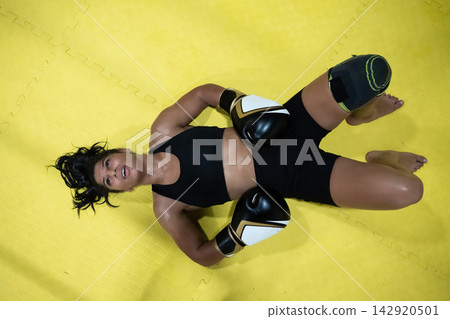 Exhausted Female Boxer Lying On Yellow Mat After Intense Training Workout Exhausted Female Boxer Lying On Yellow Mat After Intense Training Workout 142920501