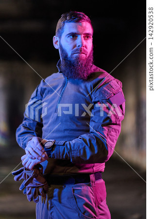 Bearded Tactical Man in Military Clothing Under Neon Lights Checking Watch With Gloves Bearded Tactical Man in Military Clothing Under Neon Lights Checking Watch With Gloves 142920538