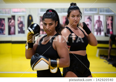 Women Boxing Partners Training in Gym With Gloves and Determined Expressions for Fitness Women Boxing Partners Training in Gym With Gloves and Determined Expressions for Fitness 142920540