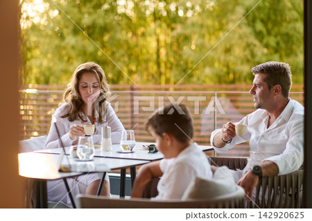 Family Enjoying Coffee Together on a Sunny Balcony Terrace During a Relaxing Morning Family Enjoying Coffee Together on a Sunny Balcony Terrace During a Relaxing Morning 142920625