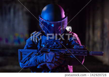Tactical Officer in Ballistic Helmet and Visor Holding Rifle in Low-Light Urban Environment Tactical Officer in Ballistic Helmet and Visor Holding Rifle in Low-Light Urban Environment 142920728