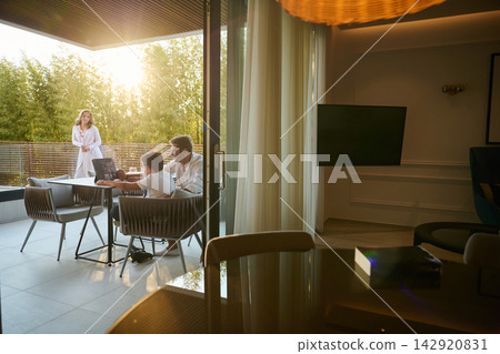 Family Relaxing on Modern Home Balcony With Father and Son Working on Laptop at Sunset Family Relaxing on Modern Home Balcony With Father and Son Working on Laptop at Sunset 142920831