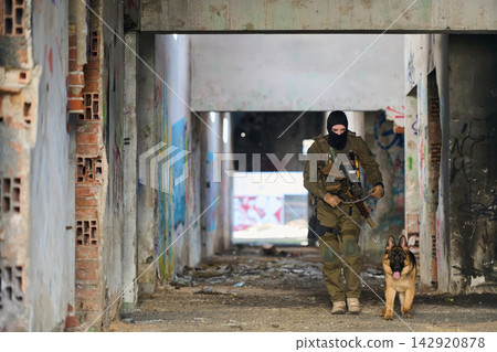 Armed Soldier With Military Working Dog Conducting Urban Patrol Through Abandoned Graffiti Covered Building Armed Soldier With Military Working Dog Conducting Urban Patrol Through Abandoned Graffiti Covered Building 142920878