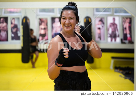 Smiling Woman Training Boxing and Fitness in Bright Kickboxing Gym During Group Workout Session Smiling Woman Training Boxing and Fitness in Bright Kickboxing Gym During Group Workout Session 142920966